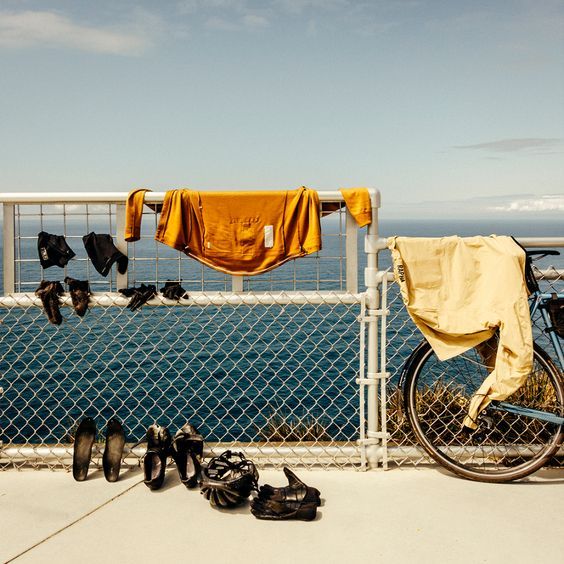 Cycling clothes and shoes arranged without a rider present beside a bicycle.