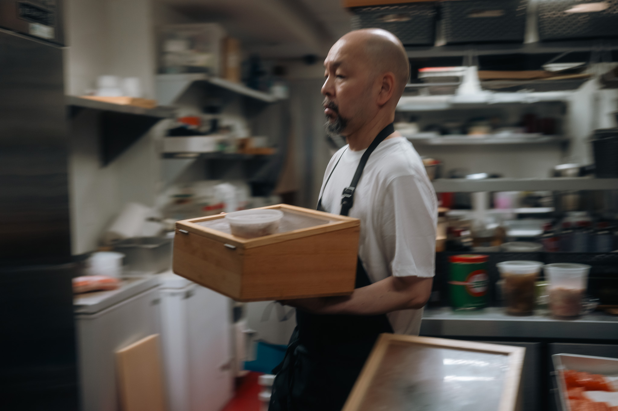 A chef carrying a wooden tray across the kitchen, motion blur catching the moment.